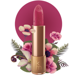 A pink natural lipstick with a floral design, displayed in a rose gold colored tube, with the brand's logo 'km' at the bottom, set against a background with a floral motif.