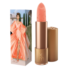 peach pink lipstick in gold cannister next to a box with a lady in a peach dress 