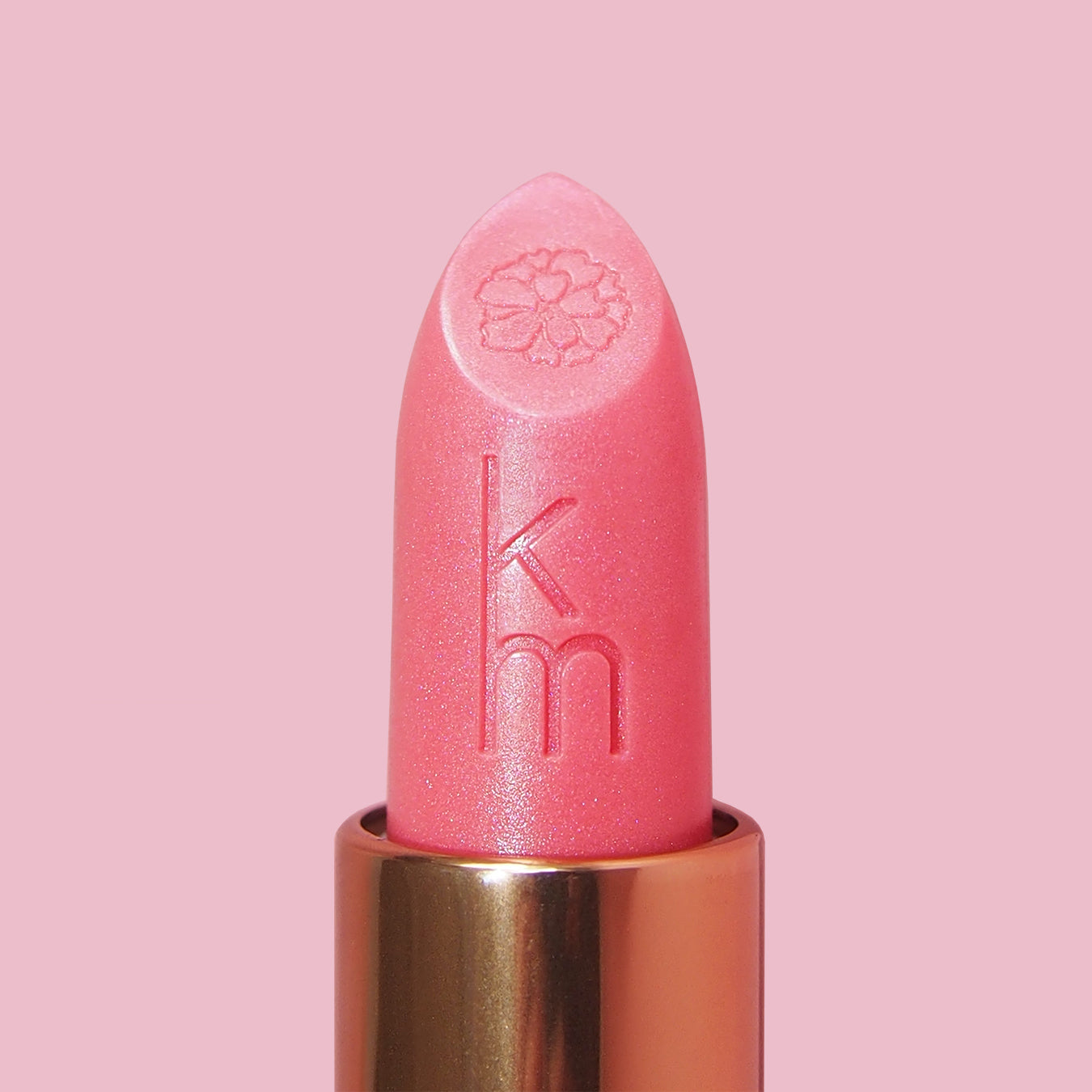 Pink lipstick with gold cap on a pink background