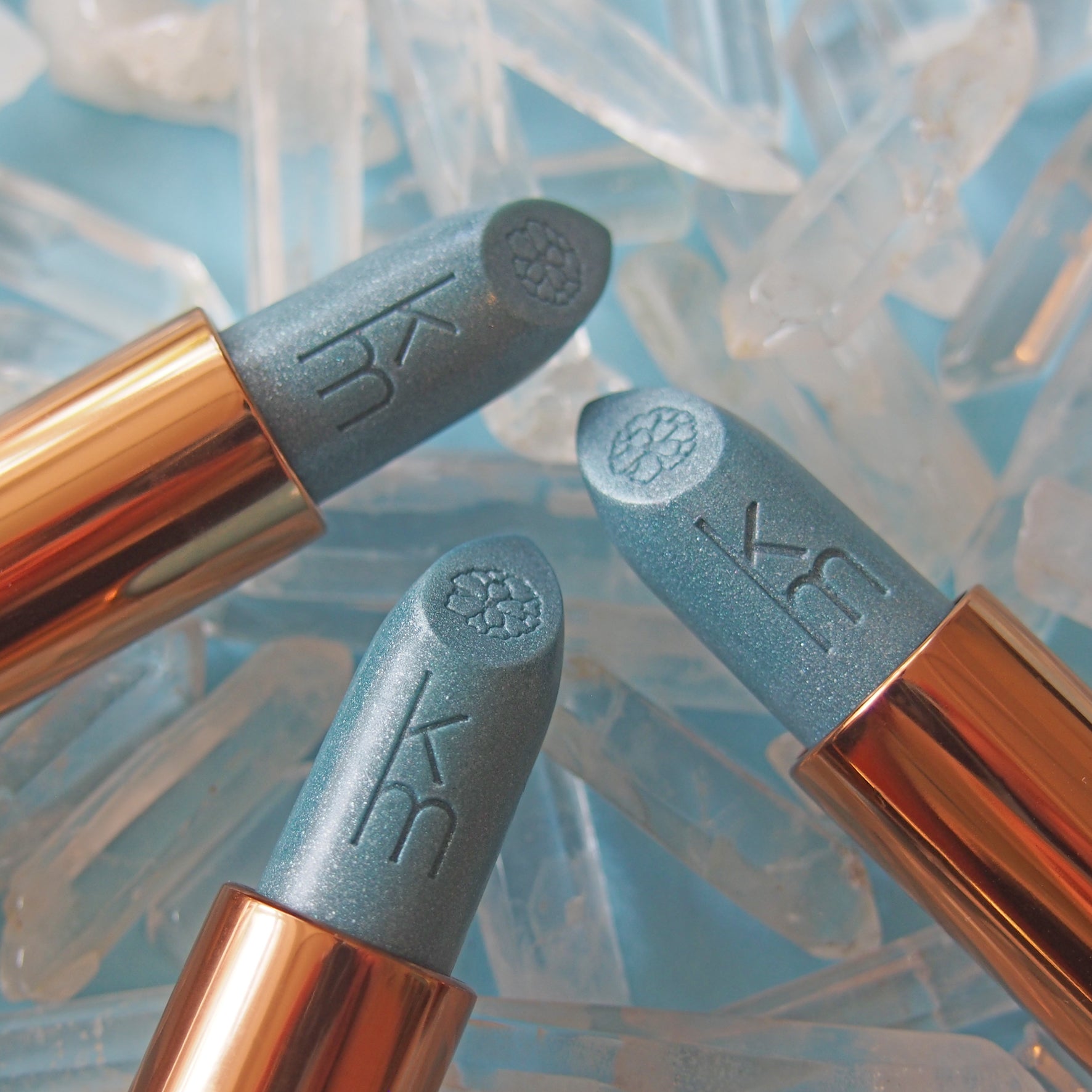 Three blue lipsticks  and blue on a light blue Icey background