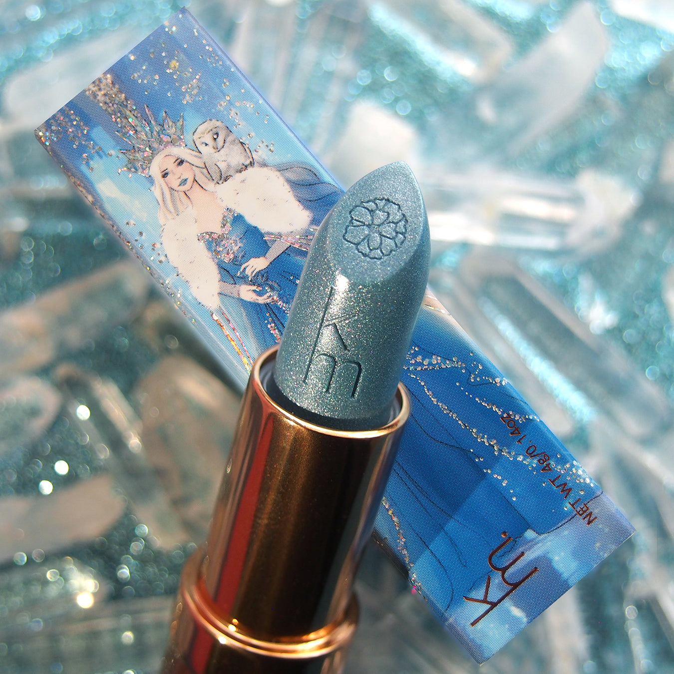 Blue lipstick with gold cap on a blue lipstick case featuring an illustration of a woman with a crown.
