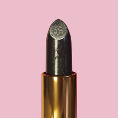 Lipstick with decorative cap on a pink background